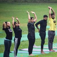 New Delhi, India, June 18 2022 - Group Yoga exercise class for people of different age in Lodhi Garden Park. International Day of Yoga, Big group of adults attending a yoga class outside in park photo