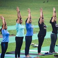 New Delhi, India, June 18 2022 - Group Yoga exercise class for people of different age in Lodhi Garden Park. International Day of Yoga, Big group of adults attending a yoga class outside in park photo