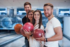 Side view. Young cheerful friends have fun in bowling club at their weekends photo