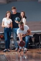 foto vertical. jóvenes amigos alegres se divierten en el club de bolos los fines de semana