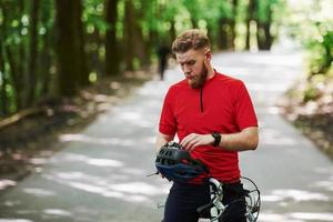 seguridad primero. ciclista en bicicleta está en la carretera asfaltada en el bosque en un día soleado foto