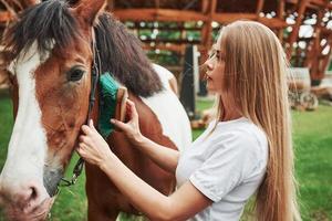 debes verte bien. mujer feliz con su caballo en el rancho durante el día foto