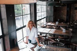 Waiting for the employee. Businesswoman with curly blonde hair indoors in cafe at daytime photo