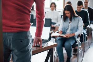 Speaker uses laptop. Group of people at business conference in modern classroom at daytime photo