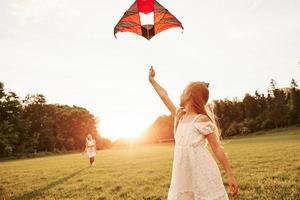 Woman is going to the child. Mother and daughter have fun with kite in the field. Beautiful nature photo