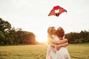 Relaxation together. Mother and daughter have fun with kite in the field. Beautiful nature photo