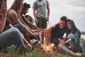 tarde en la playa. grupo de personas tienen picnic. los amigos se divierten el fin de semana foto