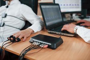 Work in progress. Suspicious man passes lie detector in the office. Asking questions. Polygraph test photo