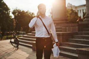 Nice sunbeam goes over head. Businessman in formal clothes with black bicycle is in the city photo