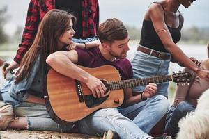 Concentrated at playing. Group of people have picnic on the beach. Friends have fun at weekend time photo