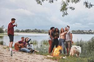 Capture the moment. Group of people have picnic on the beach. Friends have fun at weekend time photo