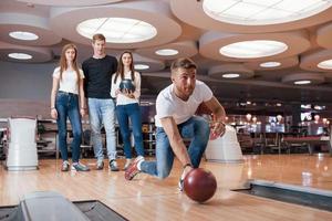 Right up in the middle. Young cheerful friends have fun in bowling club at their weekends photo