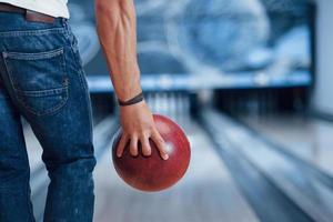 Strong hands. Rear particle view of man in casual clothes playing bowling in the club photo