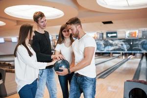 por la suerte jóvenes amigos alegres se divierten en el club de bolos los fines de semana foto