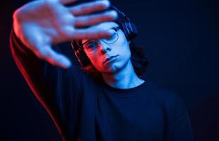 Don't disturb me. Studio shot in dark studio with neon light. Portrait of serious man photo