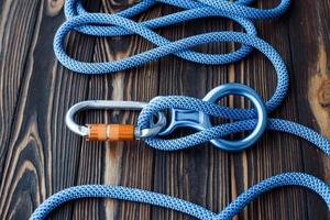 To the peak of the hill. Isolated photo of climbing equipment. Parts of carabiners lying on the wooden table