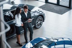 vista aérea. Cliente femenino y moderno y elegante hombre de negocios barbudo en el salón del automóvil foto