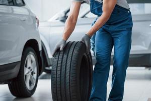 On my way. Mechanic holding a tire at the repair garage. Replacement of winter and summer tires photo