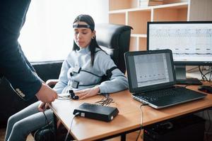 preparación, poner electrodos en los dedos. la chica pasa el detector de mentiras en la oficina. haciendo preguntas. prueba de polígrafo foto