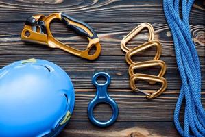 Protective helmet. Isolated photo of climbing equipment. Parts of carabiners lying on the wooden table