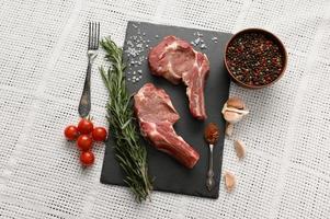Raw cowboy steak and spices on a white background. photo
