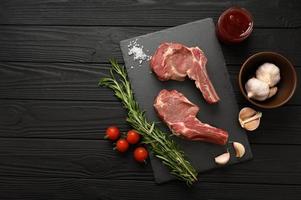 Raw cowboy steak and spices on a black wooden background. photo