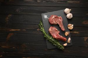 Raw cowboy steak and spices on a black wooden background. photo