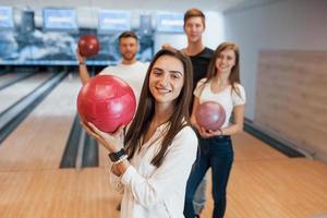 Brunette is happy to be there. Young cheerful friends have fun in bowling club at their weekends photo