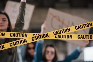 Detailed view at yellow tape. Group of feminist women have protest for their rights outdoors photo