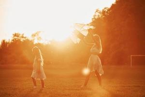 Illuminated by sunlight. Mother and daughter have fun with kite in the field. Beautiful nature photo