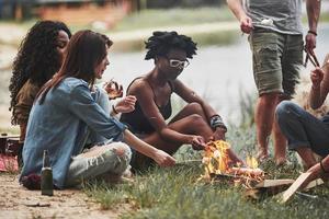 Friendship between people of other ethnicities. Group of friends have picnic on the beach. Having fun at weekend time photo