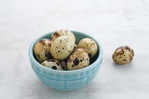 Fresh Quail Eggs served in bowl on grey background. Space for text photo