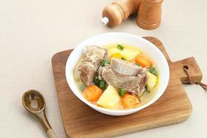 Sop Iga, Beef ribs soup, is Indonesian soup. Made from ribs, carrots, leeks, and potatoes. Served in white bowl. Selected focus photo