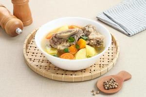 Sop Iga, Beef ribs soup, is Indonesian soup. Made from ribs, carrots, leeks, and potatoes. Served in white bowl. Selected focus photo