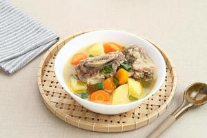 Sop Iga, Beef ribs soup, is Indonesian soup. Made from ribs, carrots, leeks, and potatoes. Served in white bowl. Selected focus photo