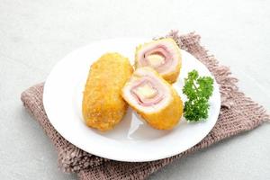 Crispy Cordon Blue, Chicken fillet roll with ham and cheese. Served in white plate on grey background. photo