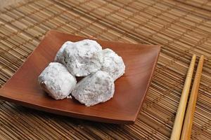 Mochi dessert with peanut paste filling served on plate on wooden board. Selected focus. photo