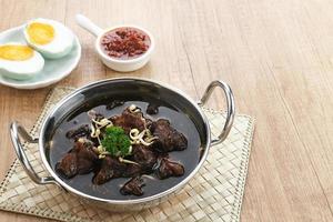 Rawon, Indonesian Traditional beef black soup. Served on a bowl with mung bean sprouts, chilli paste and salted egg photo