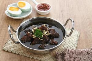 Rawon, Indonesian Traditional beef black soup. Served on a bowl with mung bean sprouts, chilli paste and salted egg photo