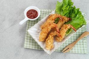 Fried breaded shrimp with vegetable on plate, served with chilli sauce photo