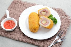 Crispy Cordon Blue, Chicken fillet roll with ham and cheese. Served in white plate on grey background. photo