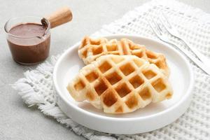 Plain Croissant Waffle or Croffle  with chocolate sauce served in white plate on grey background. Close up. photo