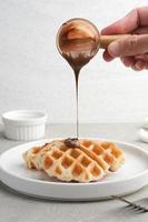 Plain Croissant Waffle or Croffle  with chocolate sauce served in white plate on grey background. Close up. photo