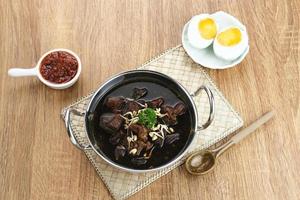 Rawon, Indonesian Traditional beef black soup. Served on a bowl with mung bean sprouts, chilli paste and salted egg photo