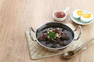 Rawon, Indonesian Traditional beef black soup. Served on a bowl with mung bean sprouts, chilli paste and salted egg photo
