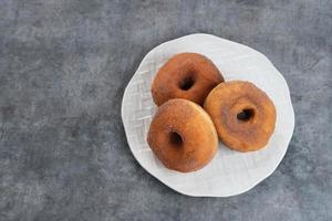 Donat Kentang, Potatoes Donut, donuts with added potato ingredients. Dusted with powdered chocolate and served on a small plate. photo