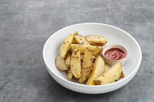 Roasted potato wedges with rosemary and herbs, served with chili sauce photo