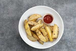 Roasted potato wedges with rosemary and herbs, served with chili sauce photo