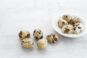 Fresh Quail Eggs served in bowl on grey background. Space for text photo