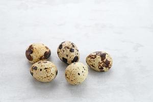 Fresh Quail Eggs served in bowl on grey background. Space for text photo